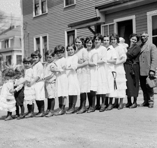 There are as many as thirteen children in this family, all lined up in a row. Now look at the car…